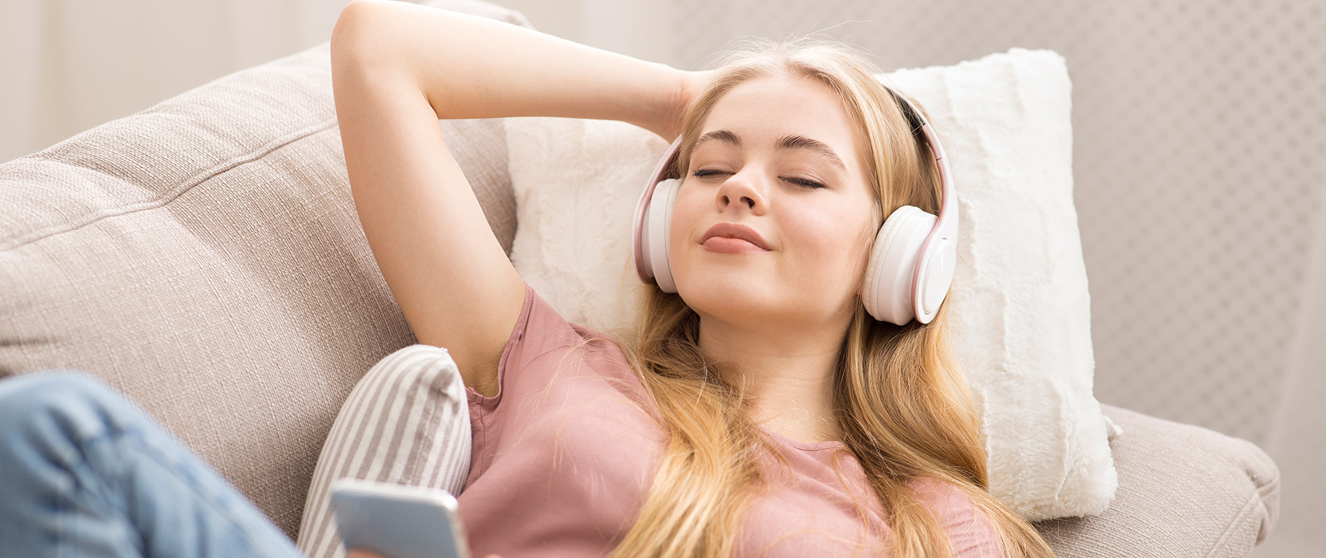 Aufnahme einer jungen, auf der Couch liegenden Dame mit Kopfhörern